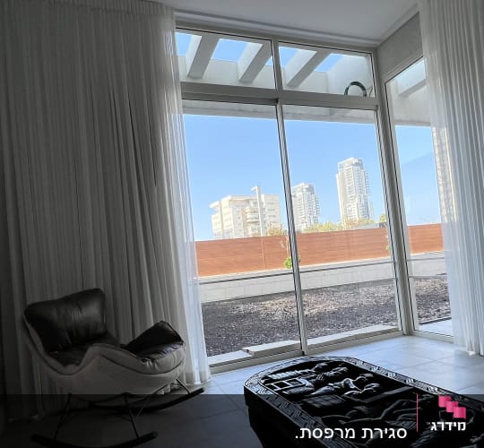 חלון זכוכית גדול עם נוף לעיר וכורסה בפנים החדר